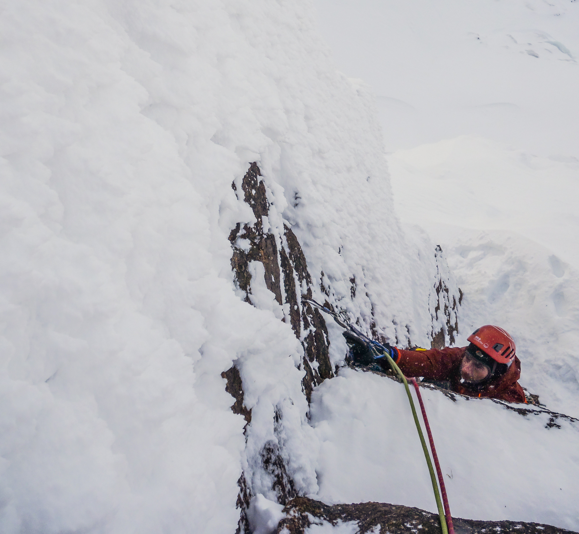 Trying hard on the crux corner and nearing the desperate mantle on to the powder covered slab above. Photo credit: Andy Inglis.