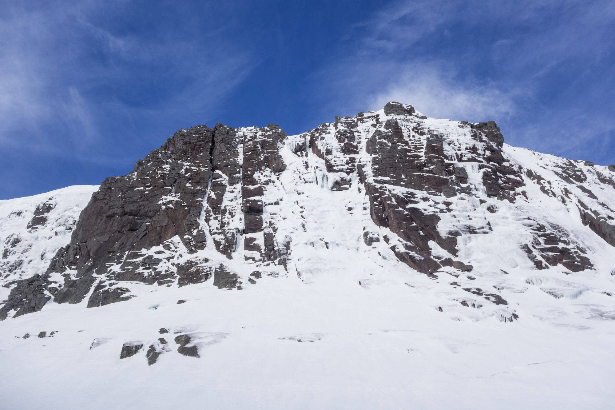 Hell's Lum Crag dripping with ice and neve. Deep Cut Chimney follows the narrow ribbon of ice into the deep slot on the left hand side of the cliff.